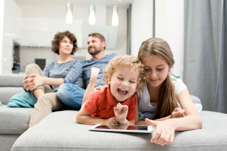YouTube Kids, app di video per bambini con contenuti sicuri e verificati: nell'immagine due bambini sorridenti guardano il canale sul tablet mentre mamma e papà sono rilassati sul divano