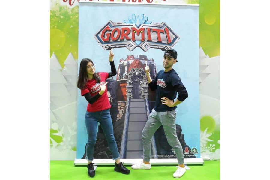 Jonny e Giada davanti al roll-up dei Gormiti, si preparano alla diretta YouTube Live da G! come Giocare presso lo stand di Giochi Preziosi